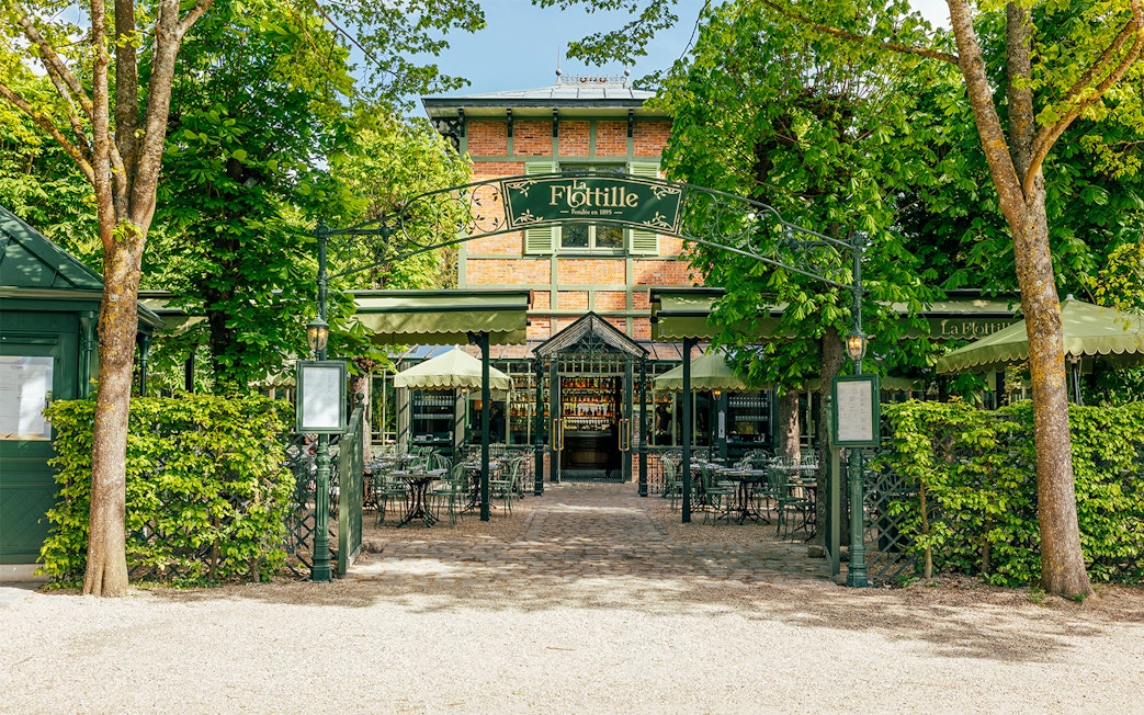 Flottille café entrance with outdoor seating in a lush garden setting.