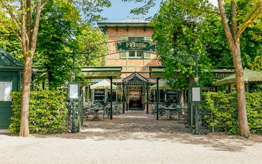 Flottille café entrance with outdoor seating in a lush garden setting.