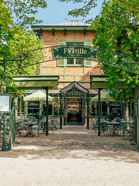 Flottille café entrance with outdoor seating in a lush garden setting.