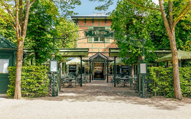 Flottille café entrance with outdoor seating in a lush garden setting.
