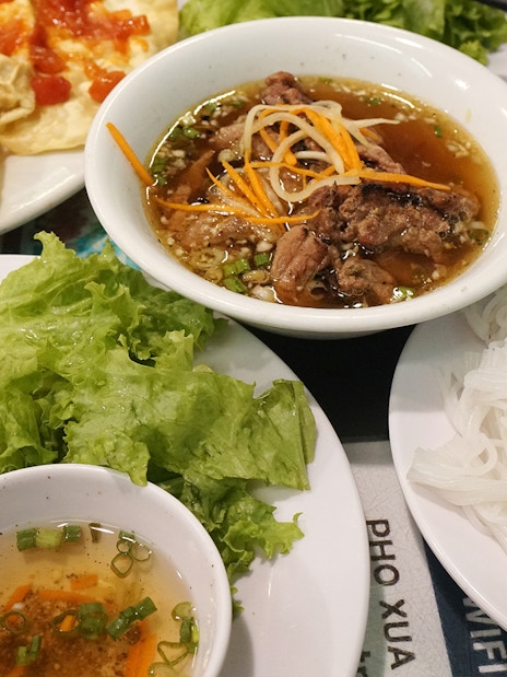 Vietnamese grilled pork with noodles, sweet sauce, and fried spring rolls at Pho Xua, Hoi An, Vietnam.