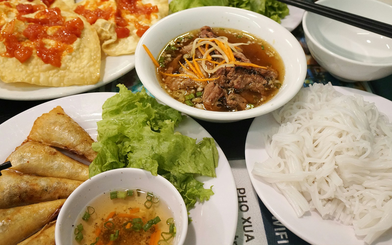 Vietnamese grilled pork with noodles, sweet sauce, and fried spring rolls at Pho Xua, Hoi An, Vietnam.