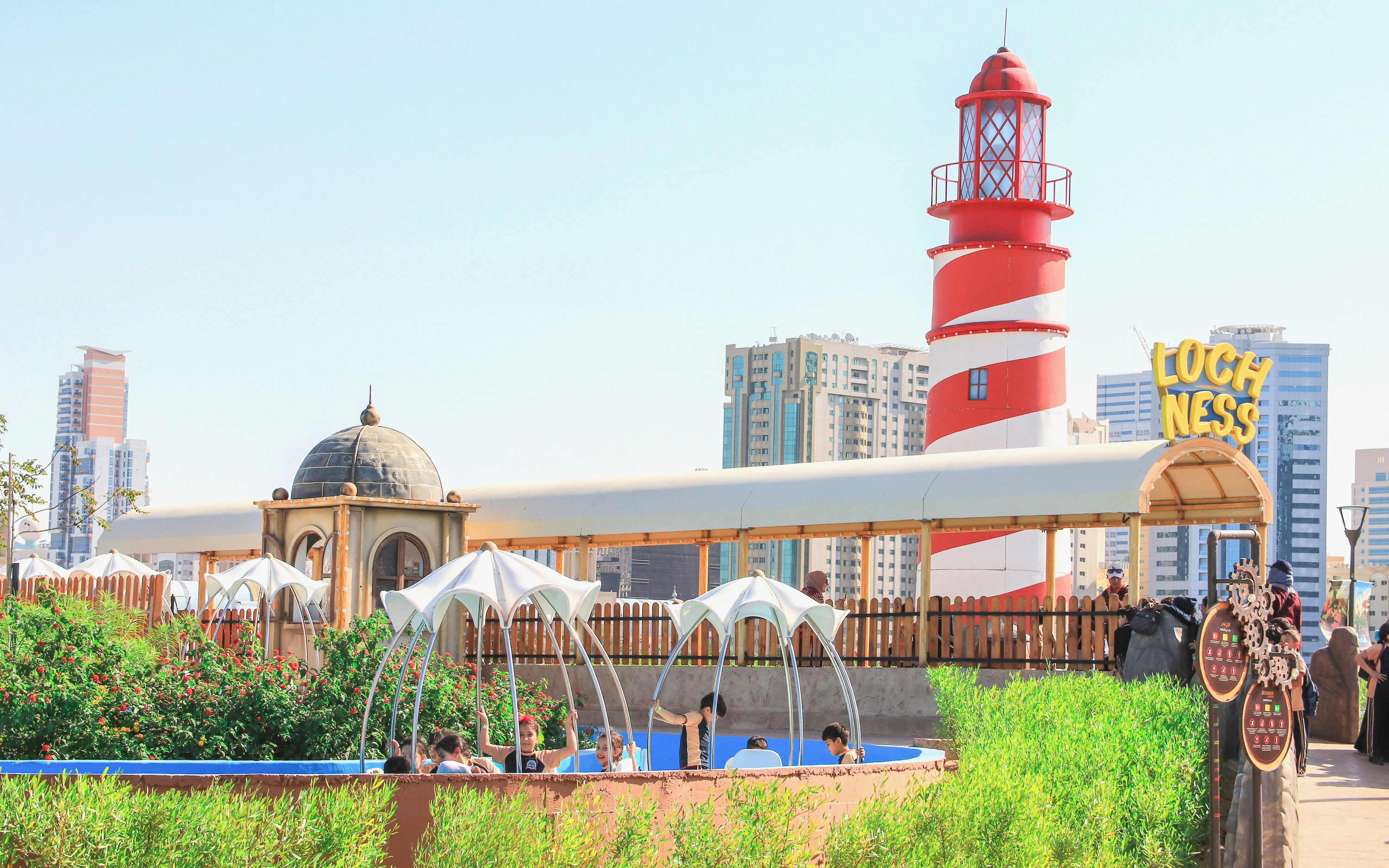 Lochness spinboat ride at Al Montazah Parks, Island of Legends with lighthouse and cityscape.