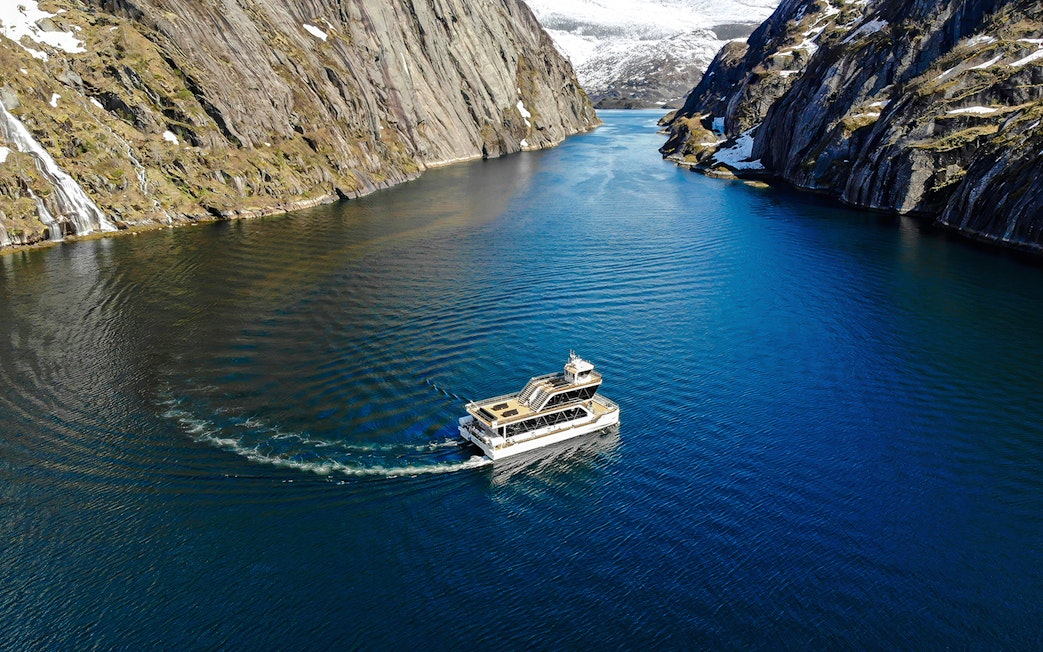 Aerial view of a boat cruising through Trollfjord, surrounded by steep cliffs, Lofoten.