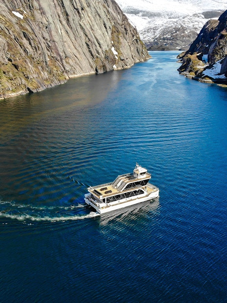 Aerial view of a boat cruising through Trollfjord, surrounded by steep cliffs, Lofoten.