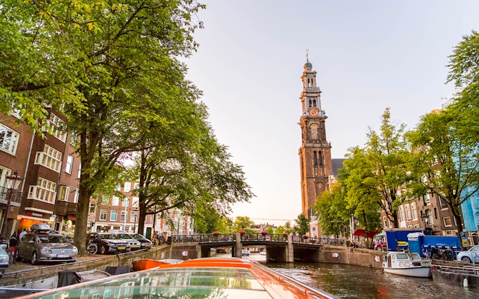 Amsterdam canal view with Westerkerk tower during a canal cruise.