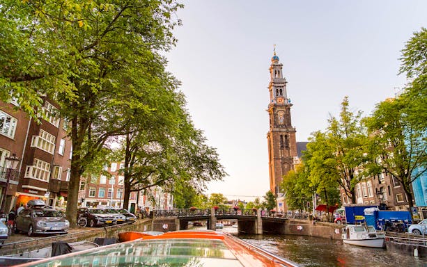 Amsterdam canal view with Westerkerk tower during a canal cruise.