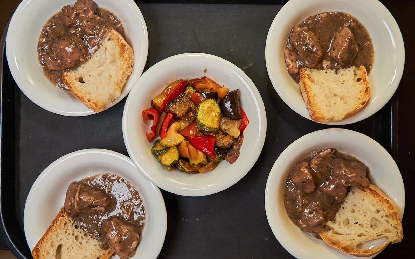 Bowls of Italian stew with bread and roasted vegetables on a Trastevere food tour.
