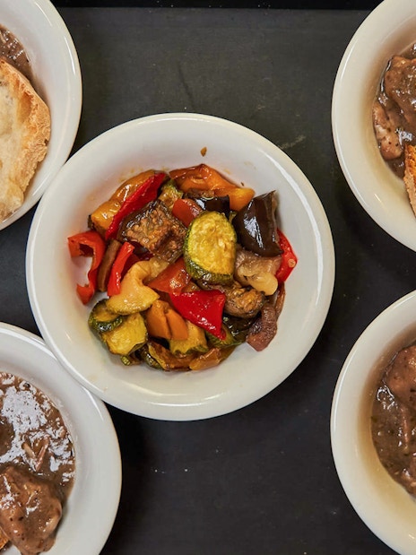 Bowls of Italian stew with bread and roasted vegetables on a Trastevere food tour.