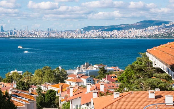 Princes' Islands view with boats on the sea and Istanbul skyline in the background.