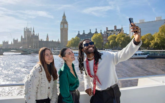 Group taking selfie on London HOHO cruise with Big Ben in background.