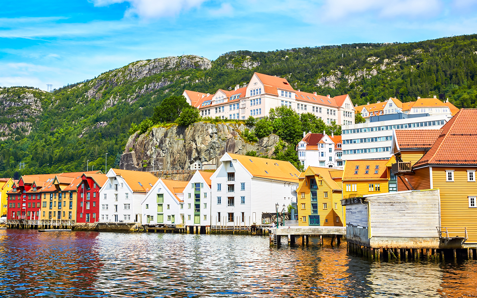 Colorful wooden houses along Wharf Skuteviken in Bergen, Norway, with hillside backdrop.