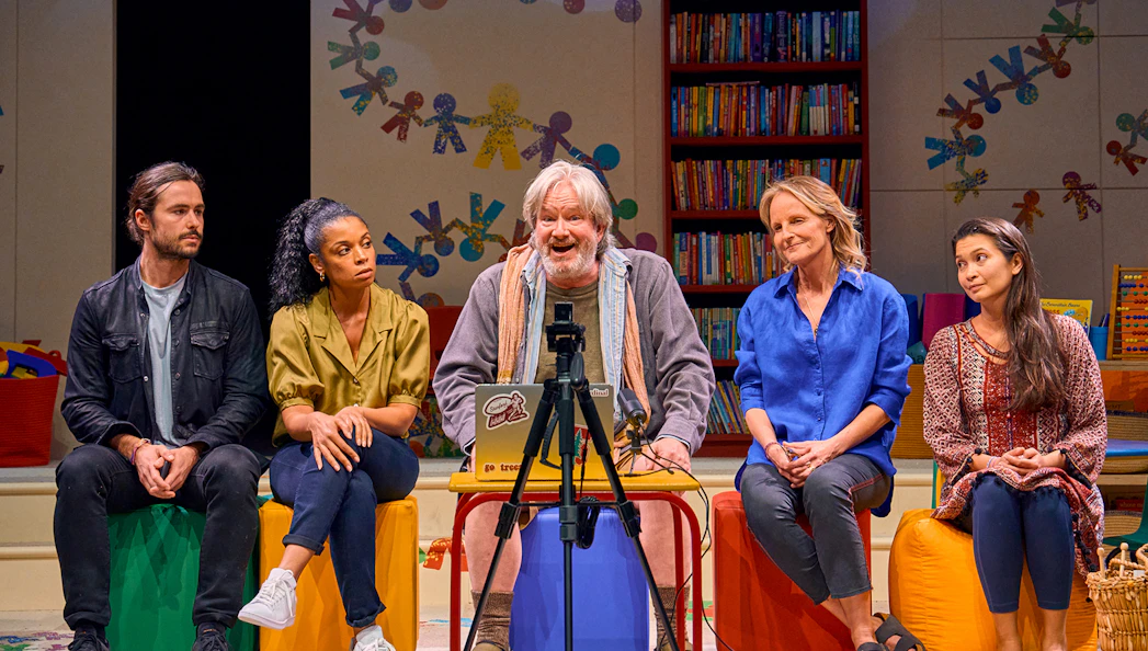 Group discussion scene from Eureka Day play with colorful classroom backdrop.