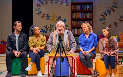 Group discussion scene from Eureka Day play with colorful classroom backdrop.