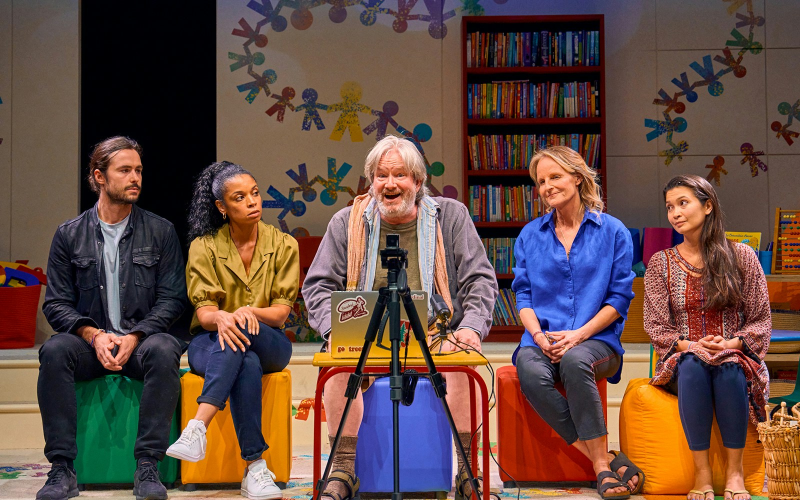 Group discussion scene from Eureka Day play with colorful classroom backdrop.