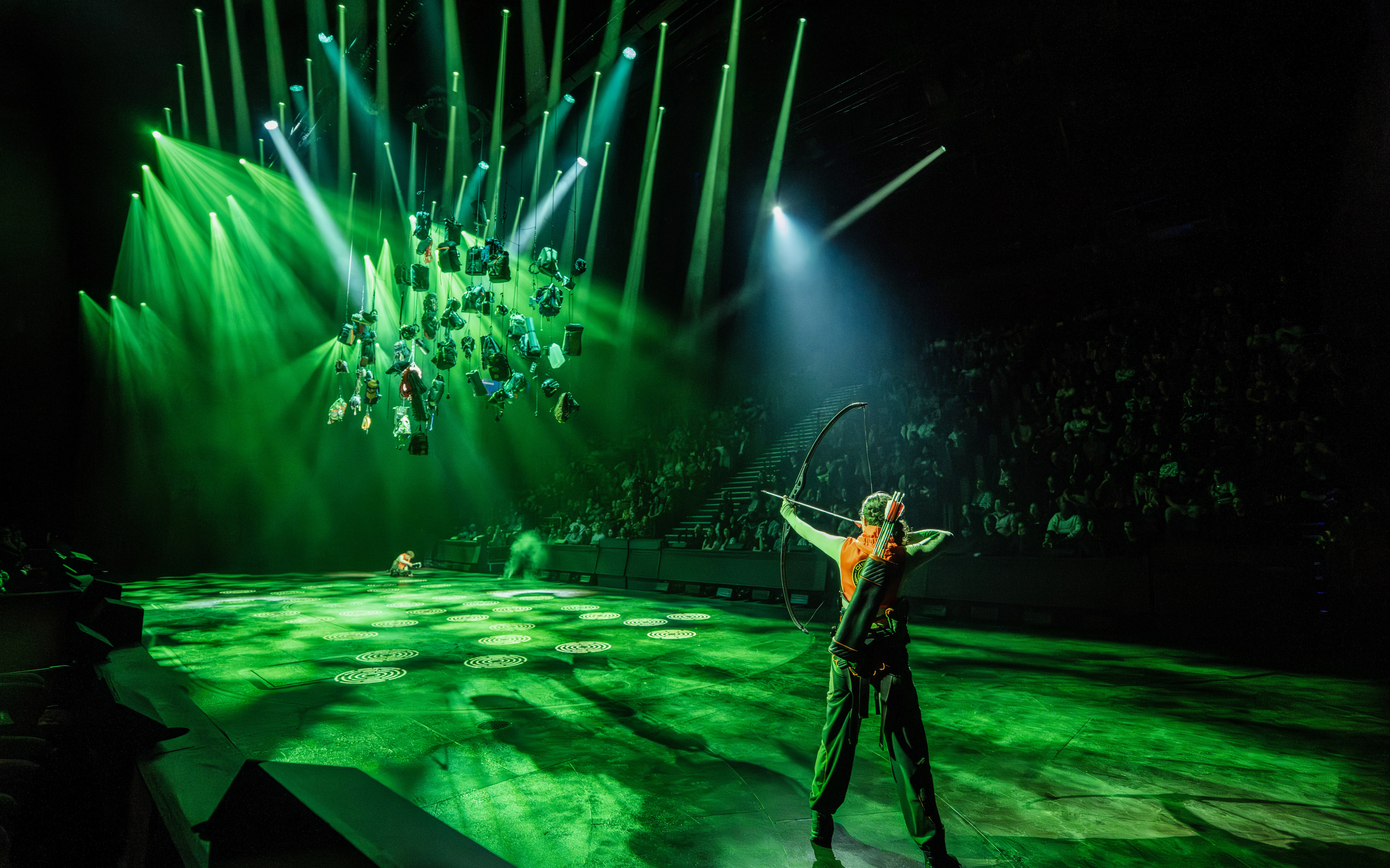 Performer with bow on stage during Hunger Games West End show.