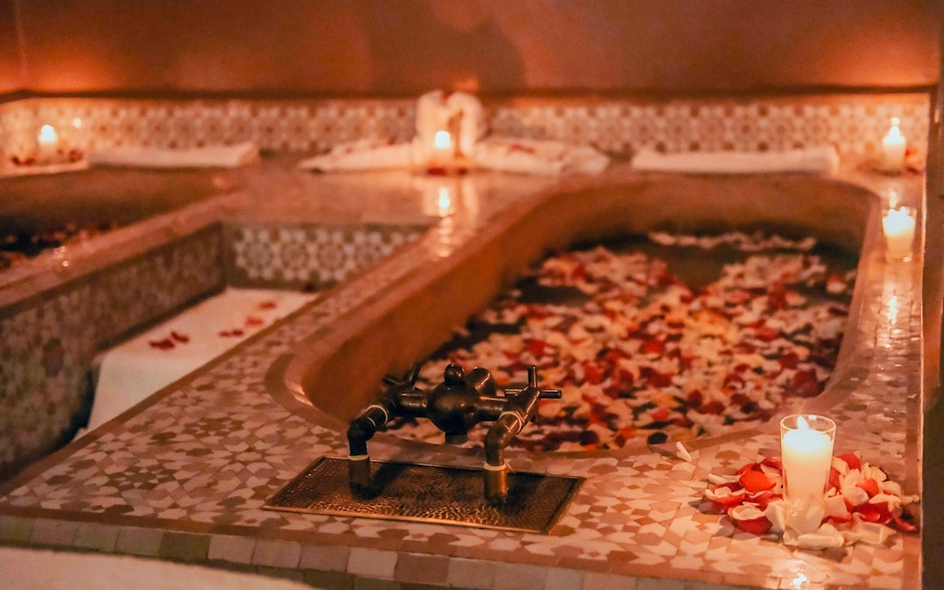Luxury steam hammam with rose petals and candles in spa setting.