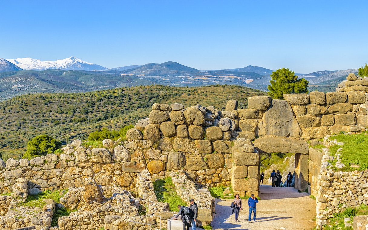 Ancient stone walls and Lion Gate at Mycenae, Peloponnese, Greece, with distant mountains.