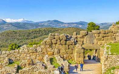 Ancient stone walls and Lion Gate at Mycenae, Peloponnese, Greece, with distant mountains.