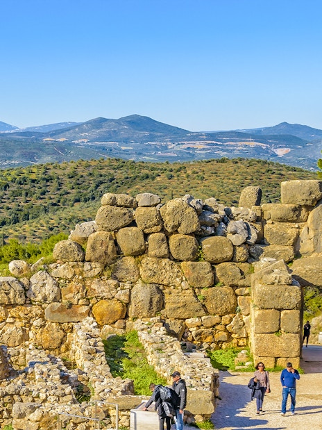 Ancient stone walls and Lion Gate at Mycenae, Peloponnese, Greece, with distant mountains.