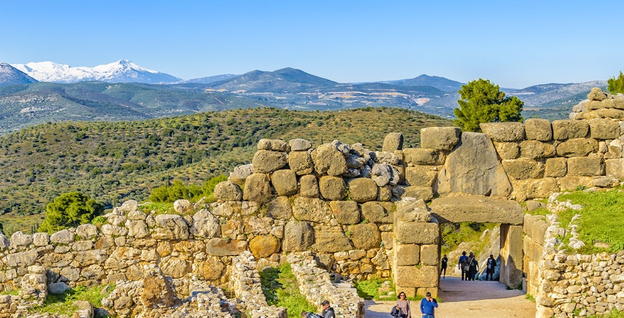 Ancient stone walls and Lion Gate at Mycenae, Peloponnese, Greece, with distant mountains.