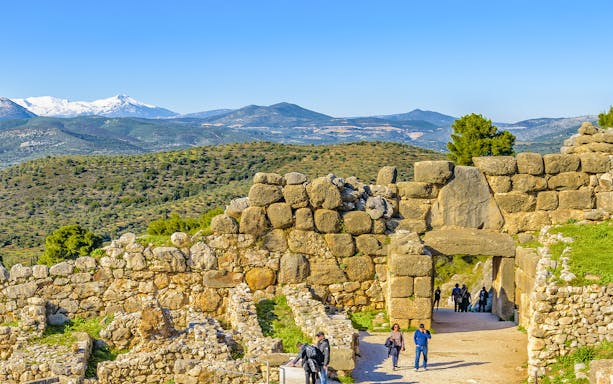 Ancient stone walls and Lion Gate at Mycenae, Peloponnese, Greece, with distant mountains.