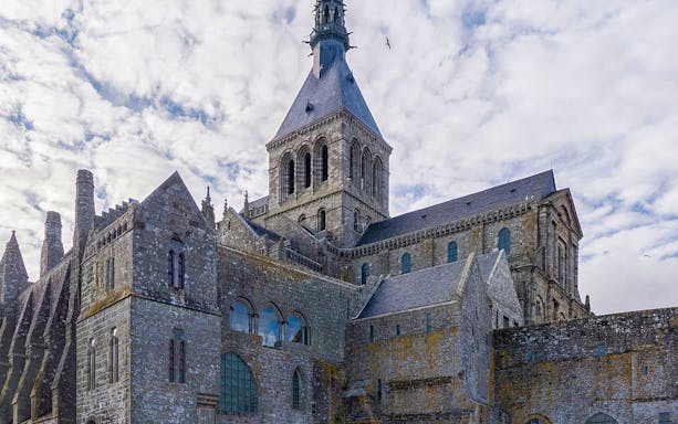 Mont Saint Michel Abbey stone architecture under cloudy sky.