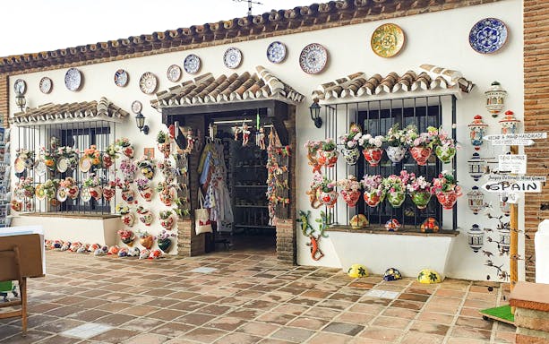 Ceramic shop with colorful pottery and floral displays in Mijas, Spain.