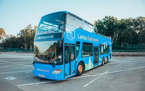 Lantau Island sightseeing bus parked in an empty lot, ready for hop-on hop-off tour.