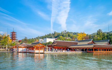 Itsukushima Shrine on Miyajima Island, Japan, with a pagoda and tourists exploring the site.