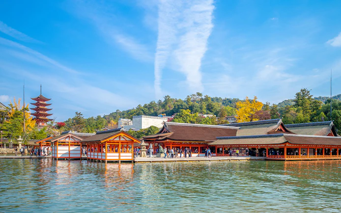 Itsukushima Shrine on Miyajima Island, Japan, with a pagoda and tourists exploring the site.