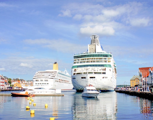 Cruise ships docked in Stavanger harbor with city center buildings on a sunny day.
