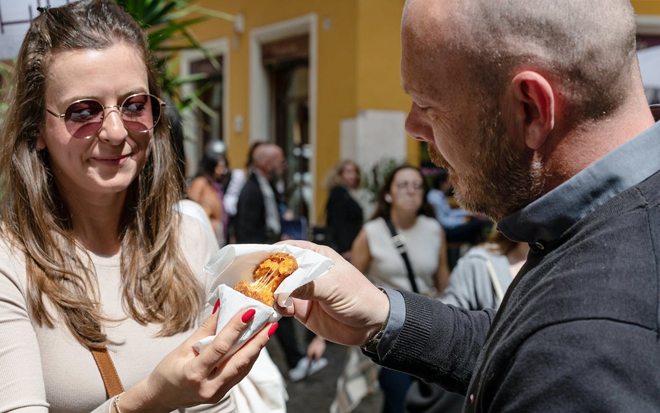Tourists enjoying street food in Campo de' Fiori, Rome.