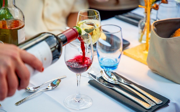 Wine being poured into a glass on an Amsterdam cruise table setting.