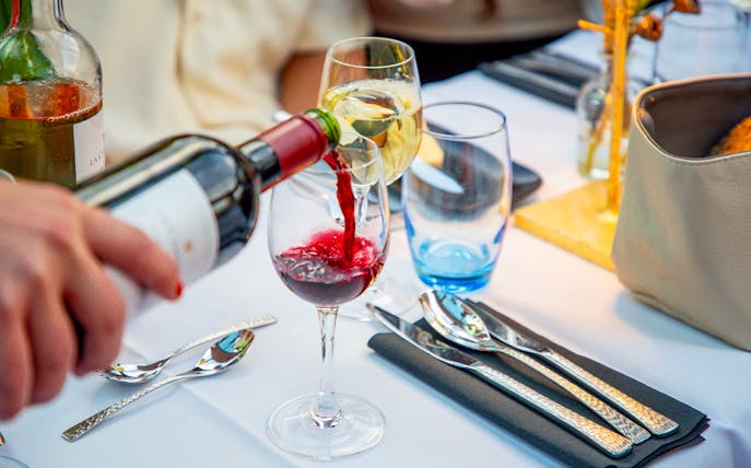 Wine being poured into a glass on an Amsterdam cruise table setting.