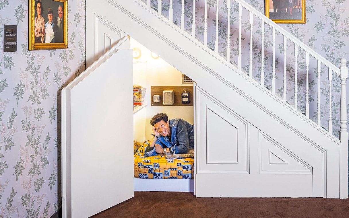 Person lying in cupboard under stairs at Harry Potter™: The Exhibition.