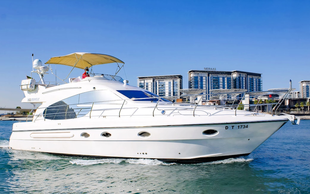 Luxury private yacht cruising near Dubai waterfront buildings.