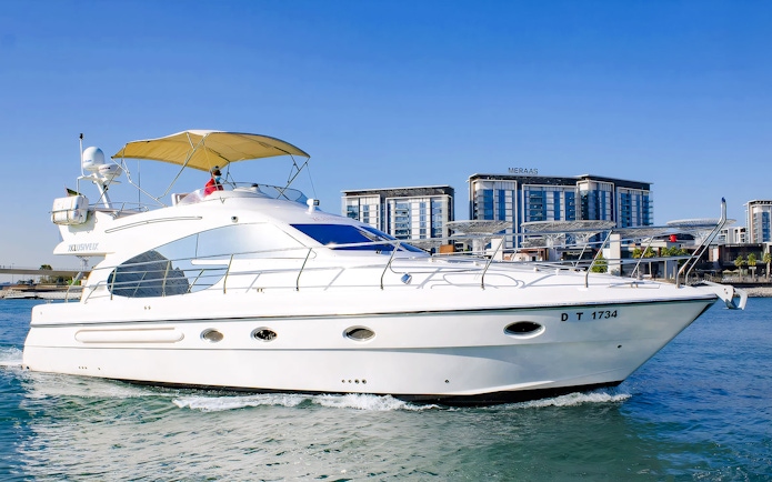 Luxury private yacht cruising near Dubai waterfront buildings.