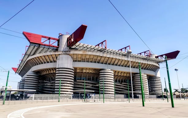 San Siro Stadium exterior view with distinctive red roof structures in Milan, Italy.