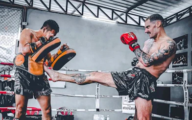 Muay Thai training session with beginners practicing kicks in Pattaya gym.