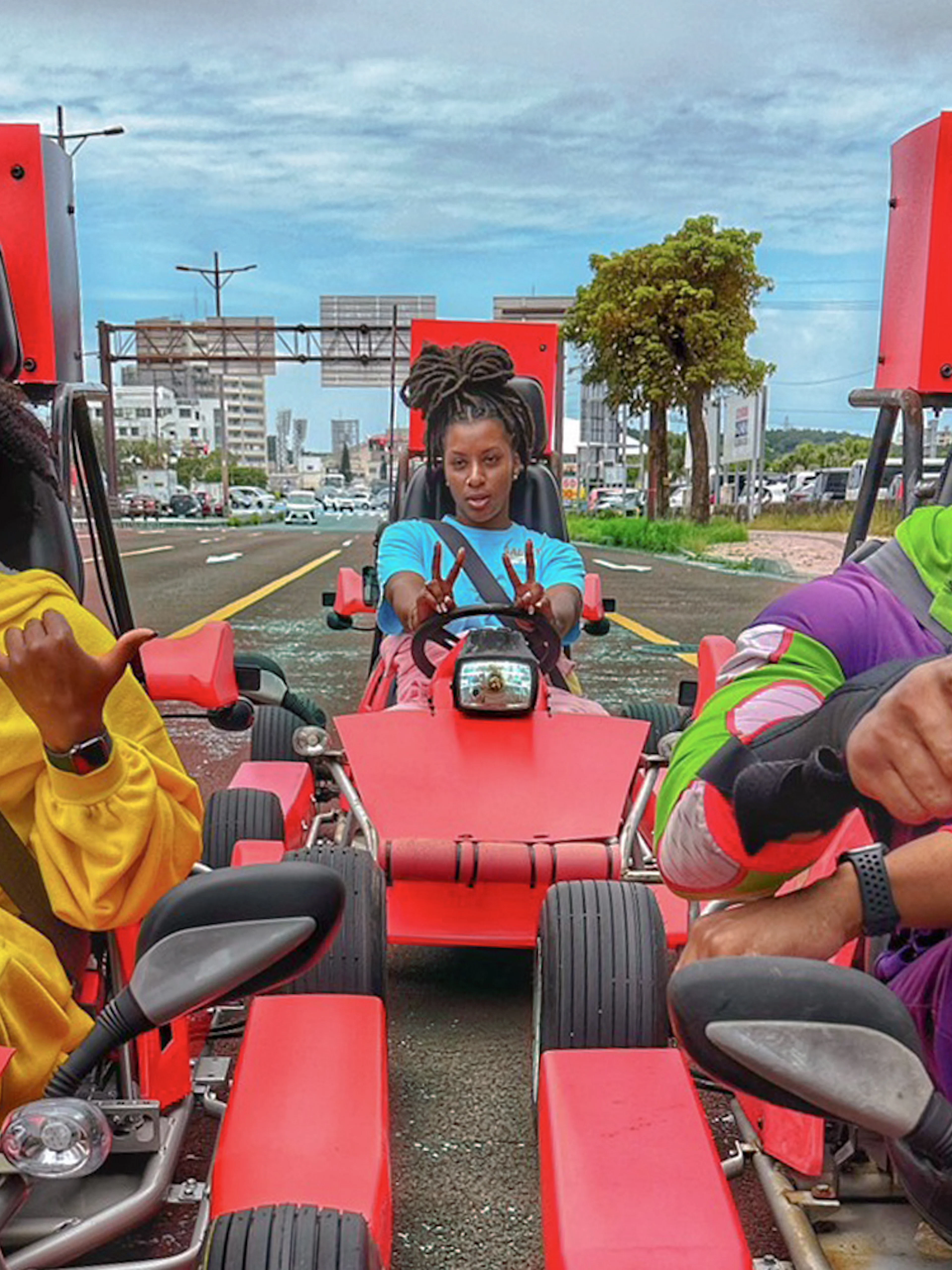 Street go-karting in Okinawa with three people in colorful outfits driving on a city road.
