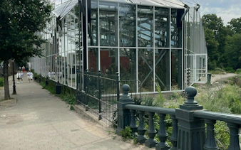Glass greenhouse along a path in Amsterdam's Plantage district, part of a self-guided city exploration game.
