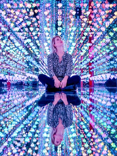 Person sitting in colorful light installation at Moco Museum Amsterdam exhibit.