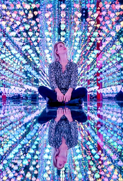 Person sitting in colorful light installation at Moco Museum Amsterdam exhibit.