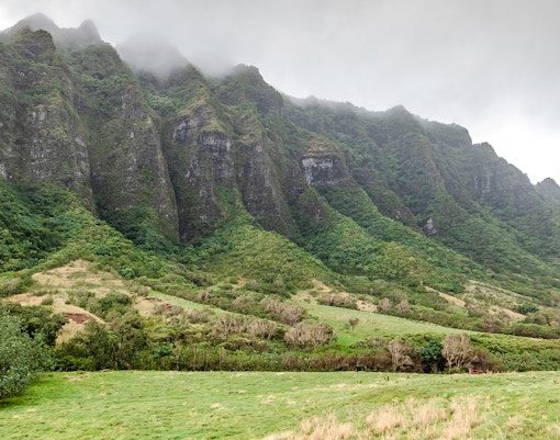 Kualoa Ranch lush green mountains in Hawaii with misty peaks.