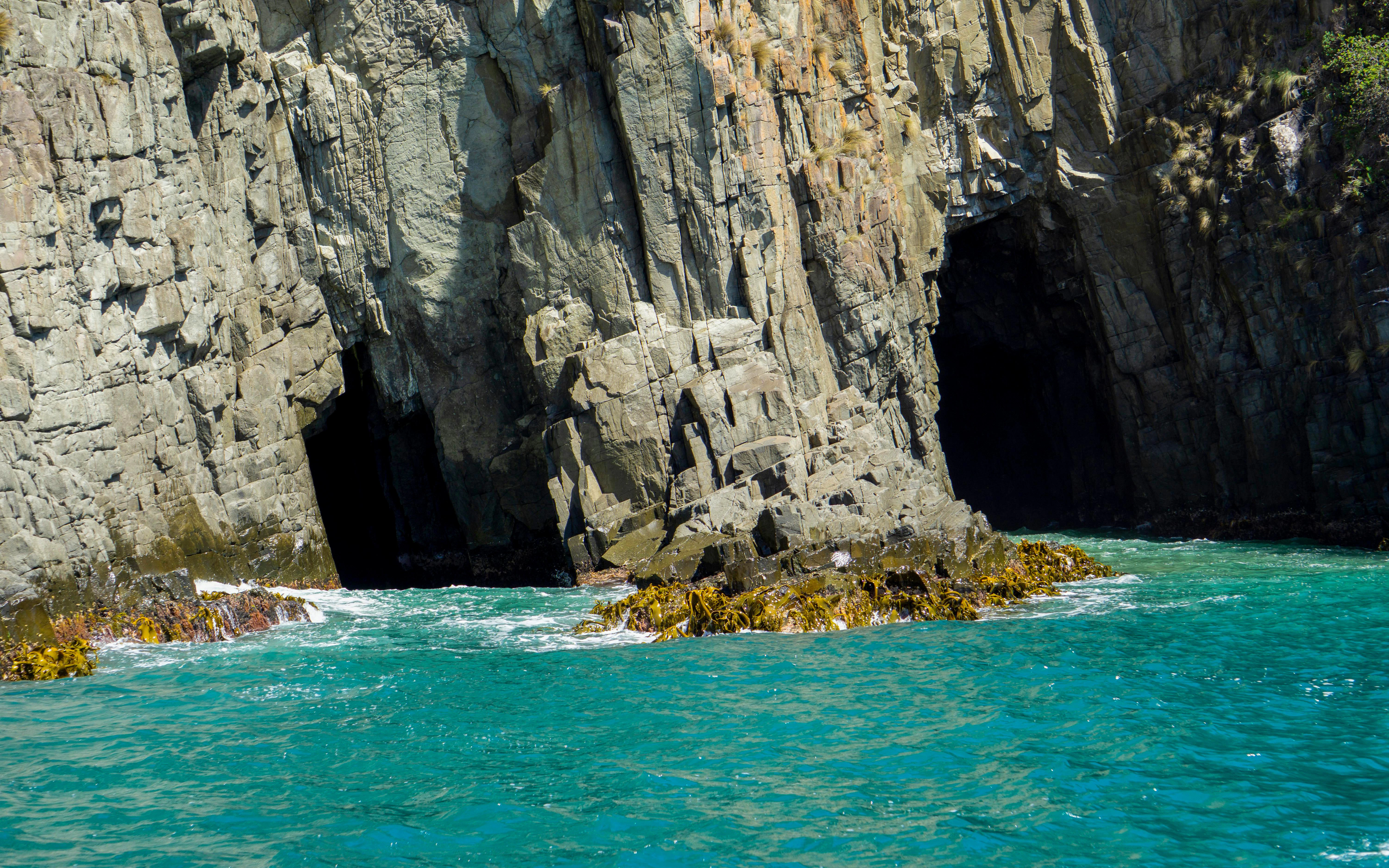 Sea caves at Fluted Cape with turquoise water, Bruny Island, Tasmania.