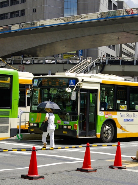 Public buses and pedestrians at a busy intersection in Osaka, Japan.