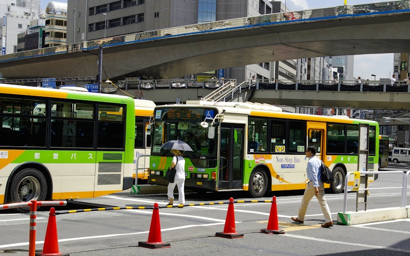 Public buses and pedestrians at a busy intersection in Osaka, Japan.