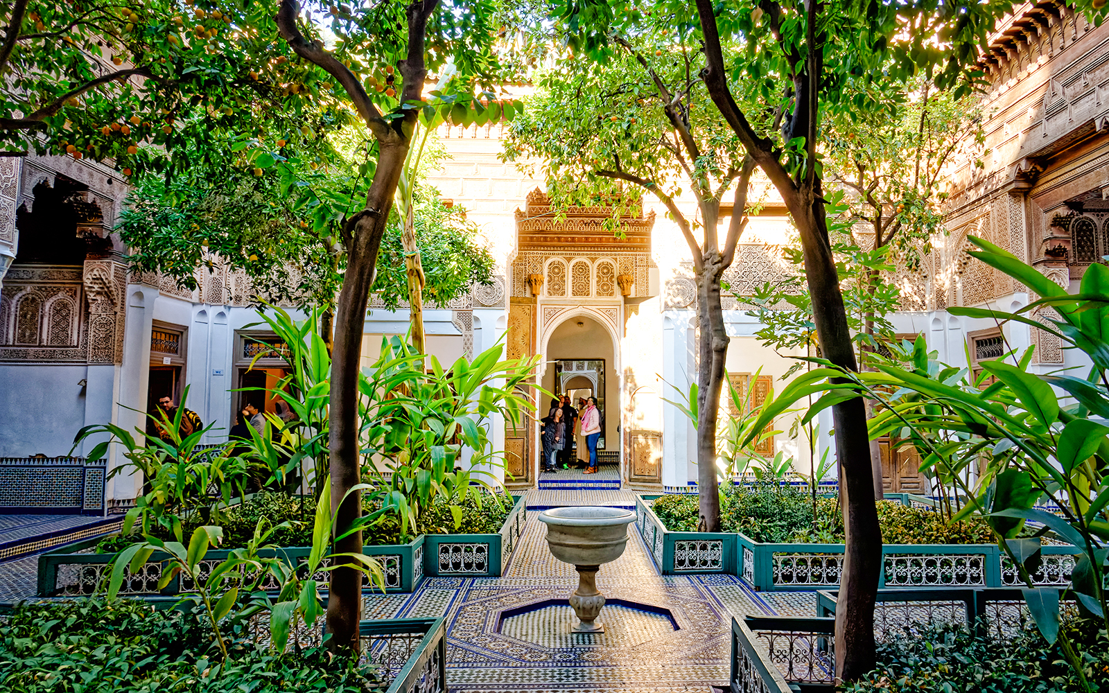 Bahia Palace courtyard with lush greenery and intricate archway in Marrakech, Morocco.
