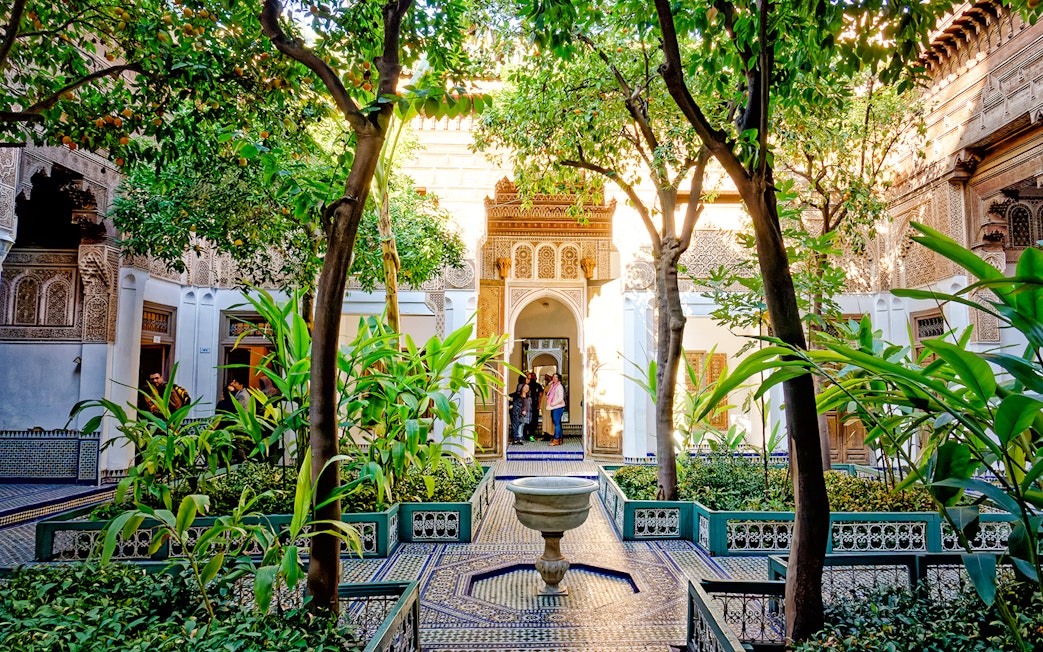 Bahia Palace courtyard with lush greenery and intricate archway in Marrakech, Morocco.